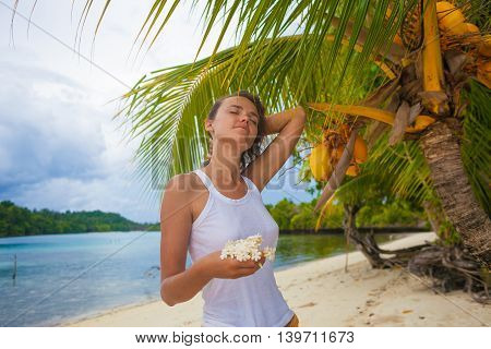 Photo young girl relaxing on beach with flowers at sunset. Smiling woman spending chill time outdoor Bali island. Summer Season Caribbean Ocean. Horizontal picture