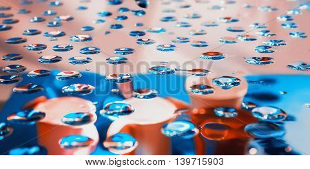 Blurred abstract blue and pink background - view through glass with drops of water on bailers and buckets out of focus.