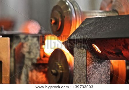 Moving the heated metal rod through the rollers in rolling mill