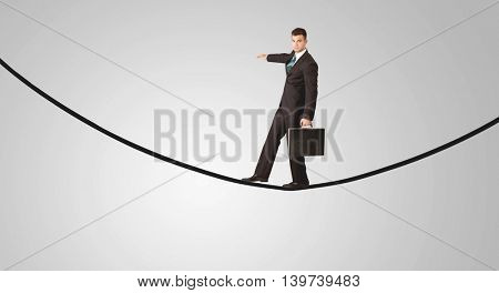 A confident smiling salesman balancing on black wire in clear grey empty space concept