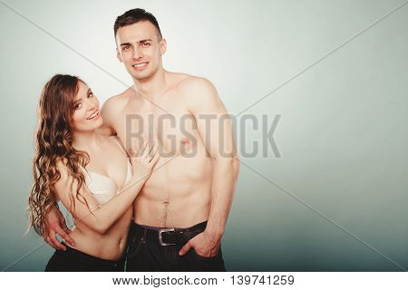 Sexy passionate young couple lovers embracing in studio. Handsome muscled half naked semi nude man and pretty gorgeous woman in lingerie. Love and passion.