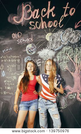 back to school after summer vacations, two teen real girls in classroom with blackboard painted together cherrful lifestyle