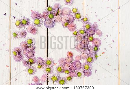 Circlet frame of purple flowers on white wooden background. Delicate romantic summer composition. Wedding style. Free space