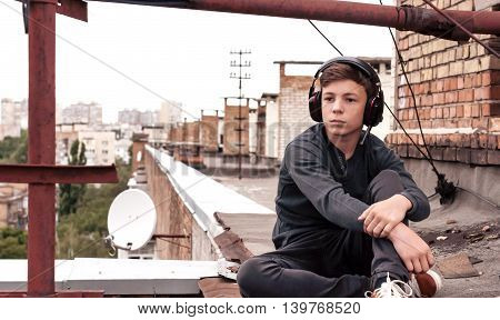 teenager on the roof of the house listens to music