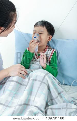 Asian Boy Having Respiratory Illness Helped By Health Professional With Inhaler.