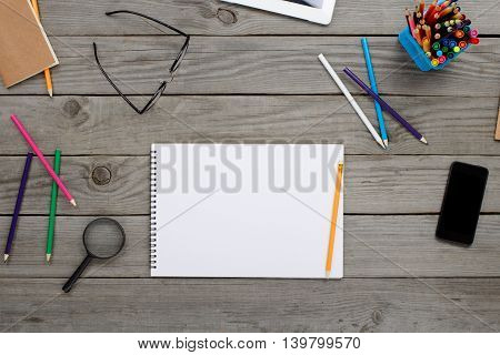 Notebook With Blank Pages Glasses Colored Pencils Snd Smartphone On Wooden Table In Home Office Top View