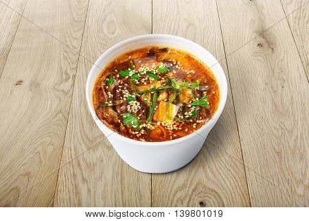 Japanese cuisine hot food delivery - miso soup at brown wooden background in white plastic plate