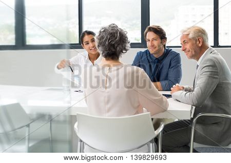 Multiethnic business people holding a meeting to sum up the results of the year. Group of happy team during a meeting in a board room. Young businesswoman showing a business graph of the company.