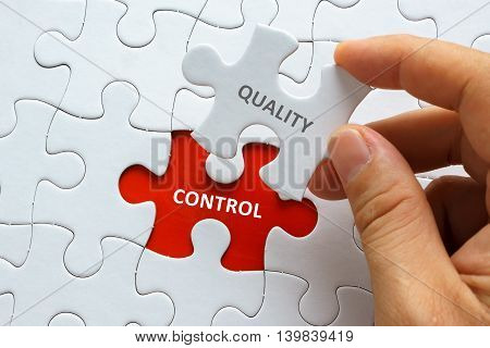Hand Holding Piece Of Jigsaw Puzzle With Word Quality Control.