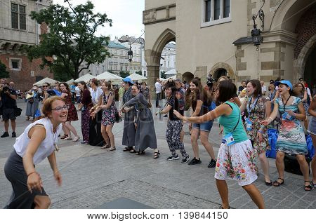 CRACOW POLAND - JULY 24 2016: Pilgrims of World Youth Day sing and dance on the Main Square in Cracow. Poland