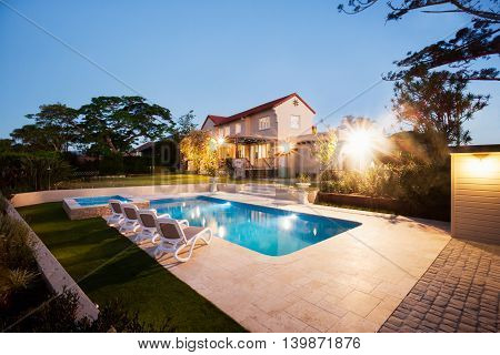 House And A Garden With A Pool Illuminate With Lights