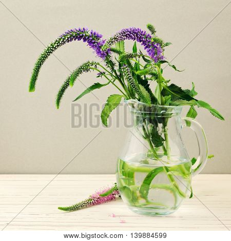 Flowers in glass pitcheron white wooden table