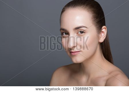 Beauty fashion vogue style face of caucasian brunette with elegant make-up blue eyes natural lips touching perfect skin. Close-up studio portrait isolated. Black background with grey spot. Toned.