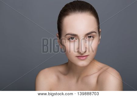 Beauty fashion vogue style face of caucasian brunette with elegant make-up blue eyes natural lips touching perfect skin. Close-up studio portrait isolated. Black background with grey spot. Toned.