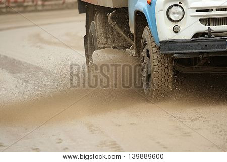 Road brush sweeper machine cleans dirt road and splashing mud