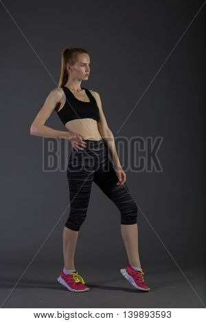 slim female in activewear doing posin on gray low key perfect sport woman