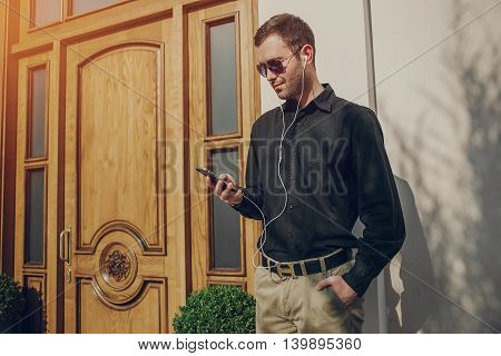 A guy in a nice town, walking, listening to music and taking pictures themselves on the phone
