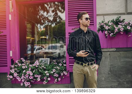 A guy in a nice town, walking, listening to music and taking pictures themselves on the phone