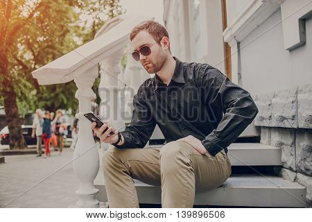 A guy in a nice town, walking, listening to music and taking pictures themselves on the phone