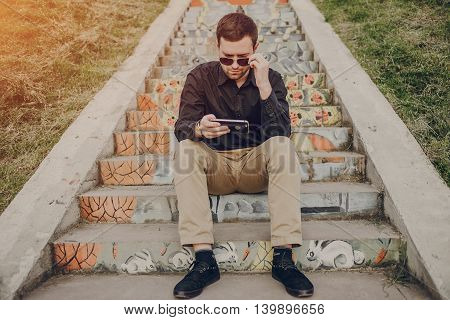 A guy in a nice town, walking, listening to music and taking pictures themselves on the phone