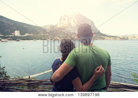 Embracing man and girl looking to hte mountain and harbour - vintage color.