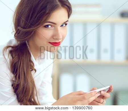 Businesswoman sending message with smartphone in office