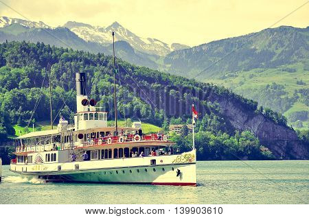 Vitznau Switzerland - June 10 2010: The passenger tourist steam boat leaving pier in central Switzerland.