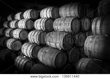 Wine barrels stacked in the old cellar of the winery. Black and white