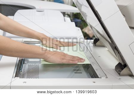 woman hands putting a sheet of paper into a copying device