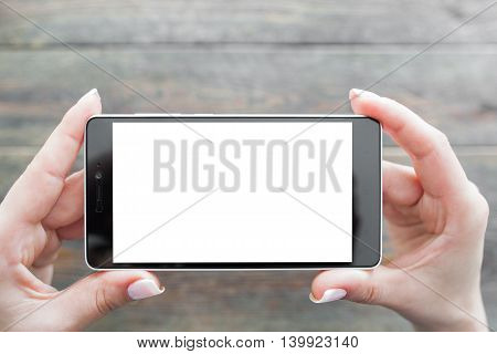 Snapping picture on smartphone, wooden background. White empty screen of gadget. Taking photo on mobile phone concept.