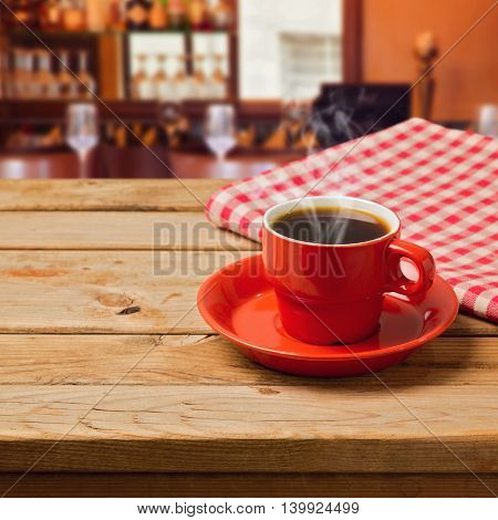 Coffee cup with checked tablecloth on wooden table