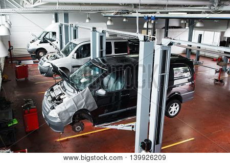 Industrial car lifting at modern repair shop. Minibuses service maintenance at professional workshop.