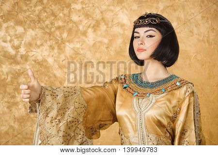 Thumbs up. Glamorous closeup portrait of beautiful sexy stylish brunette young woman model with bright makeup with gold jewelery. Cleopatra