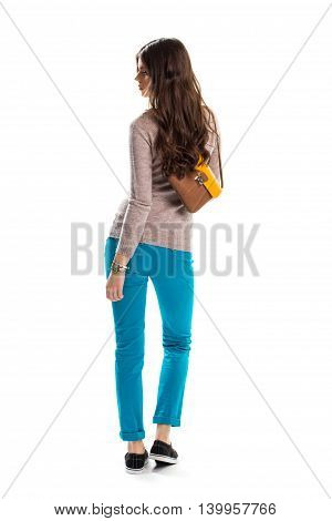 Woman in sweater looking back. Bag and black sneakers. Casual apparel for youth. New strecth pants.