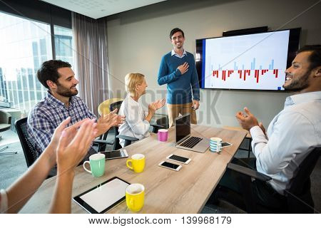 Coworkers applauding a colleague after presentation in the conference room