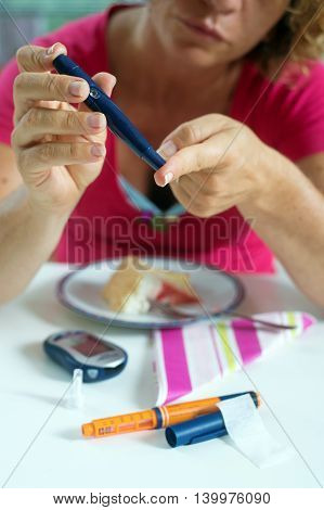 Close up of a woman using lancelet on finger to take sample of blood sugar.