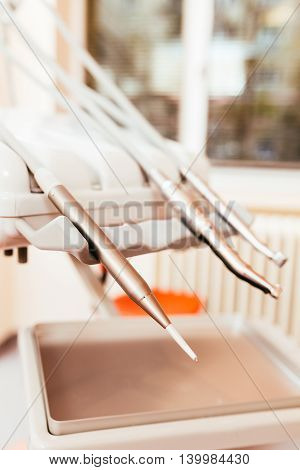 Dentist's handpieces placed on dentist tool rack with focus on air water spray.