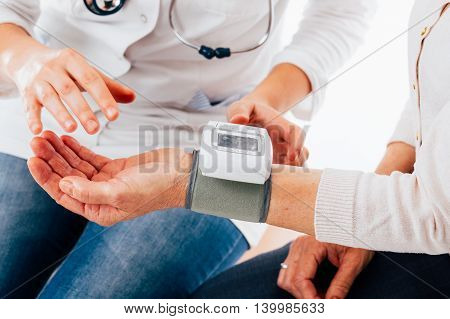 Doctor giving instructions of using a hand tensiometer - isolated on white