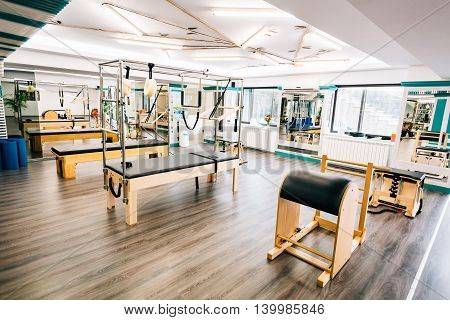 Room full of pilates equipment: exochairs ladder barrel reformer cadillac and trapeze table