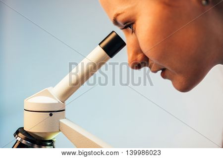 Passionate young researcher looking through microscope lens
