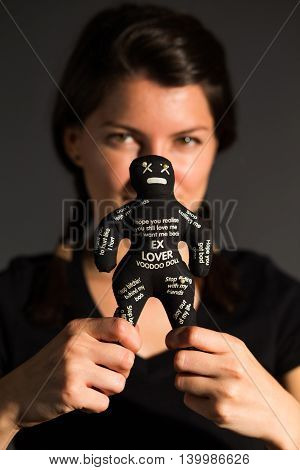 Woman holding a black voodoo doll by its legs in her hands