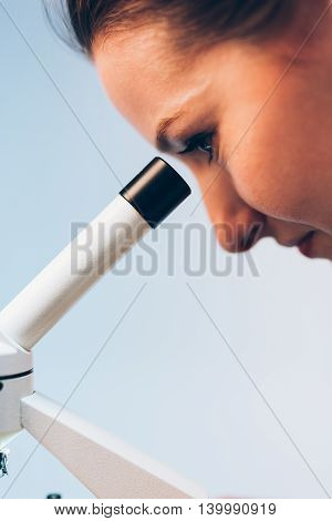 Young researcher looking through a medical microscope