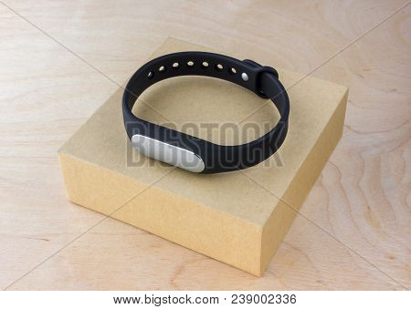 Fitness Bracelet On The Box Of The Kit. A Smart Bracelet Pedometer And A Box From It On A Wooden Tab