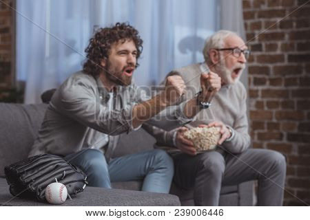 Screaming Adult Son And Senior Father Cheering On Baseball Team And Watching Game At Home
