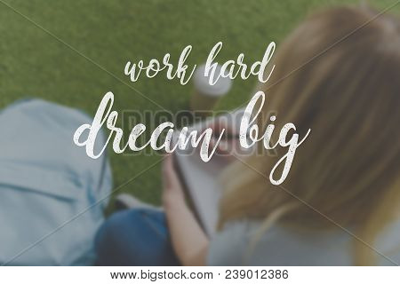 Cropped Shot Of Young Student Sitting On Grass And Writing In Notebook, Work Hard Dream Big Inscript