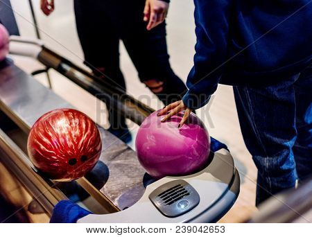 Girl picking up a bowling ball hobby and leisure concept