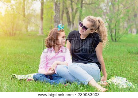Mother And Daughter Resting On The Nature On The Green Grass, Resting, Smiling In The Summer In Sunn