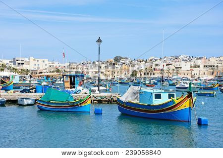 Marsaxlokk, Malta - April 1, 2017 - Traditional Maltese Dghajsa Fishing Boats In The Harbour With Wa