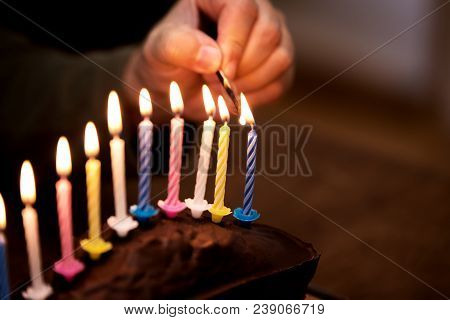 Male Hand Is Lightning Up Some Colorful Candles On A Marble Cake