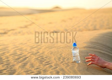 Hand Try To Catch The Bottle Of Water On Sand Desert In Hot Temperature. Concept Of To Die Of Thirst